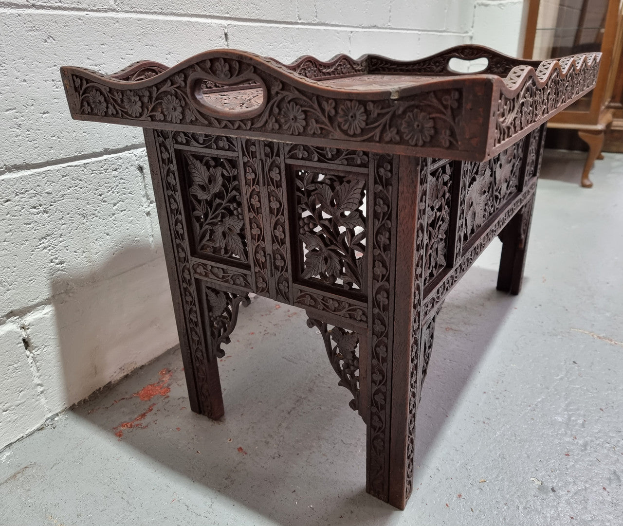 Anglo Indian folding occasional table with lift-up tray top. The tray has brass inlay and ornate carvings. The bottom of the table folds down and it is in good original condition.