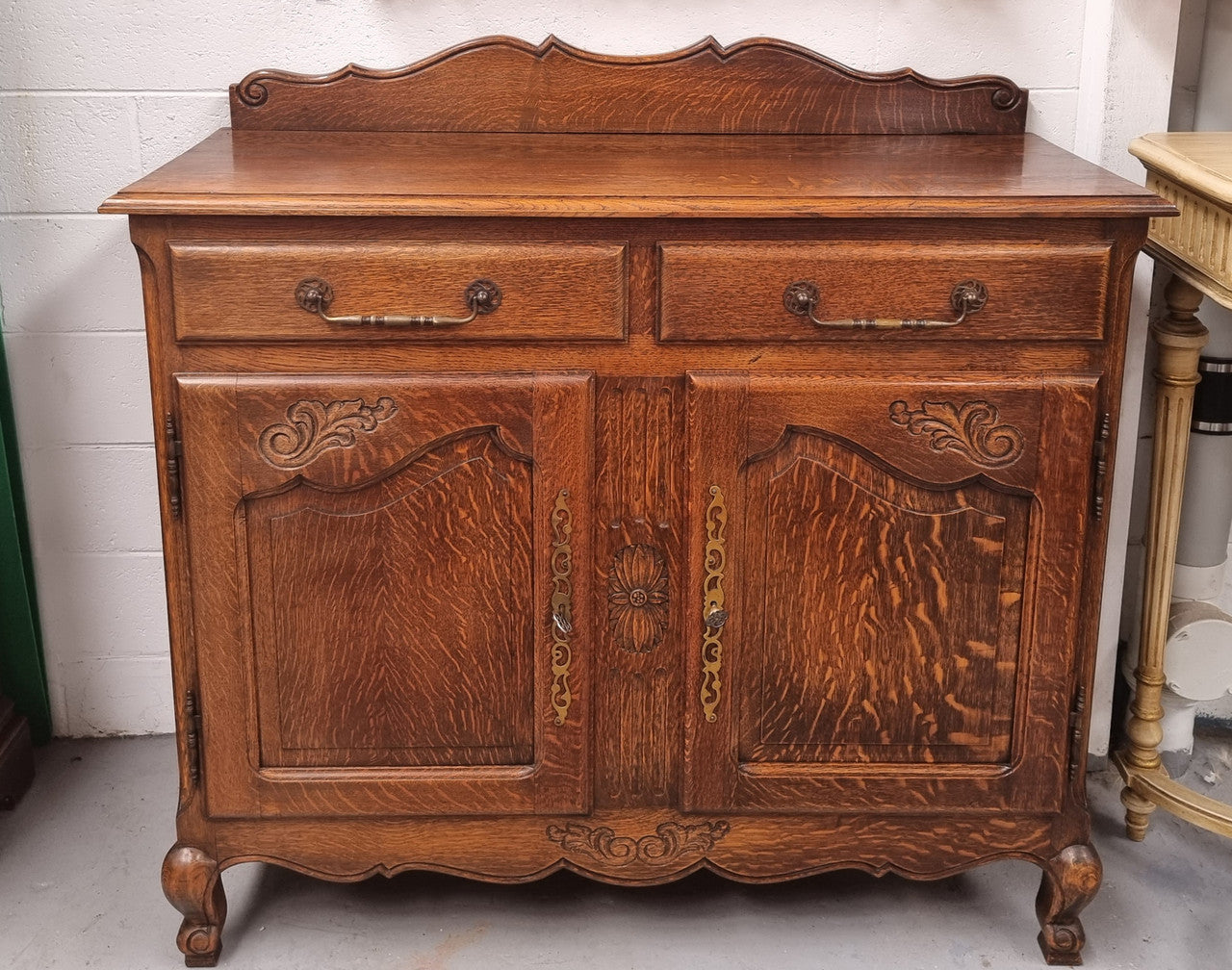 French Louis XV style Oak two door, two drawer sideboard. It is of pleasing narrow proportions and has one interior shelf. It has been sourced from France and it is in good original detailed condition.