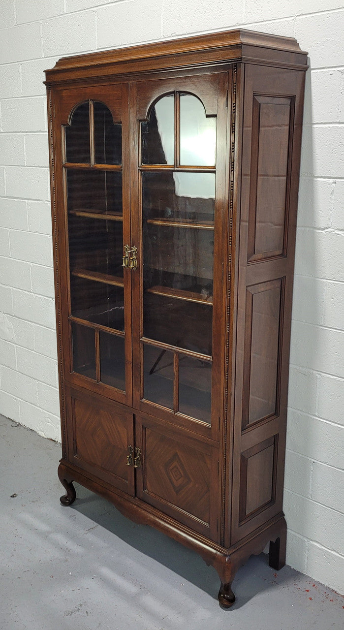 English Walnut two door bookcase with original glass. It has three adjustable shelves and hidden storage below behind two smaller doors. It is in food original condition.