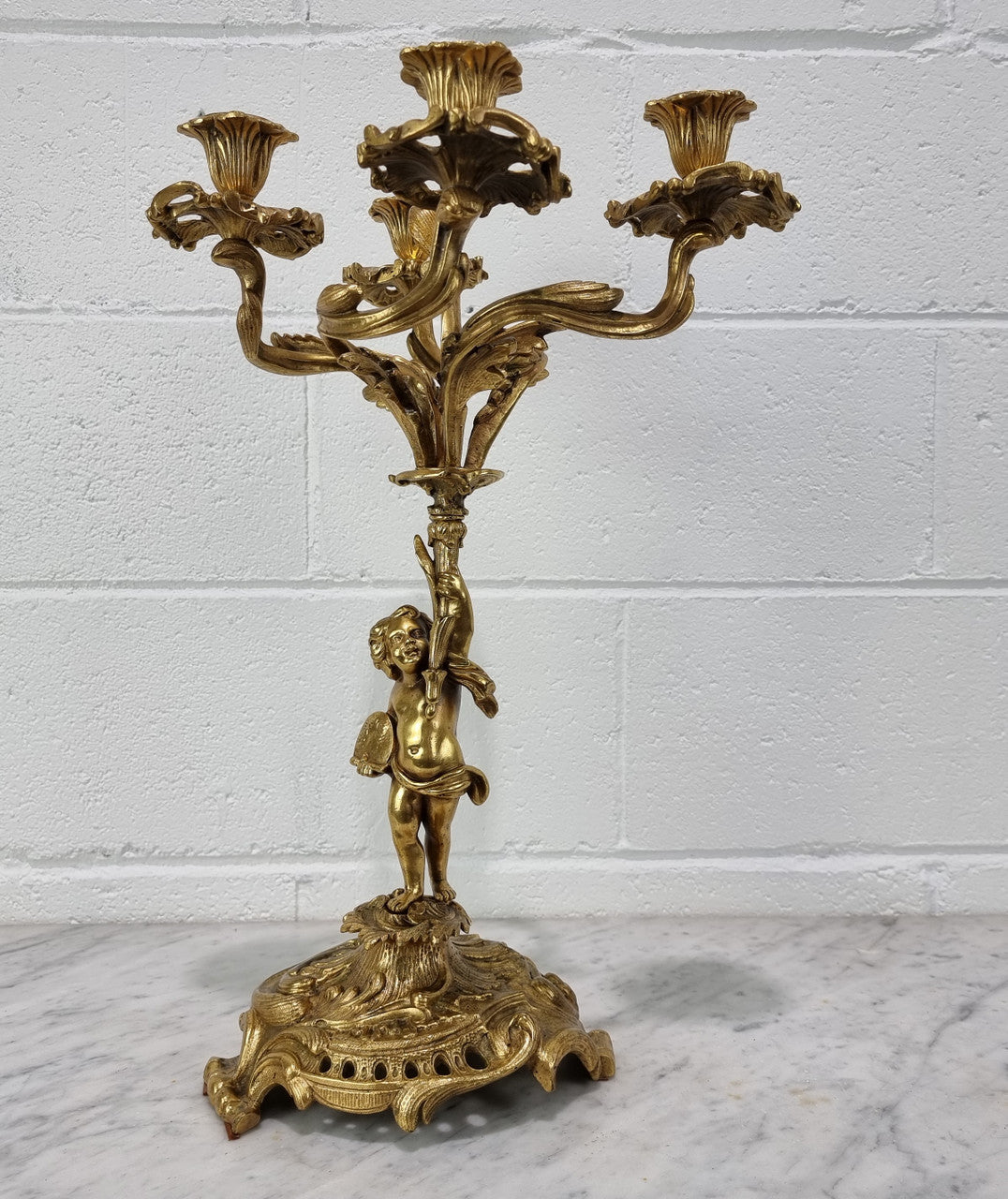 A pretty 19th Century French gilt bronze candelabra featuring a cherub. In good condition. Circa 1880.