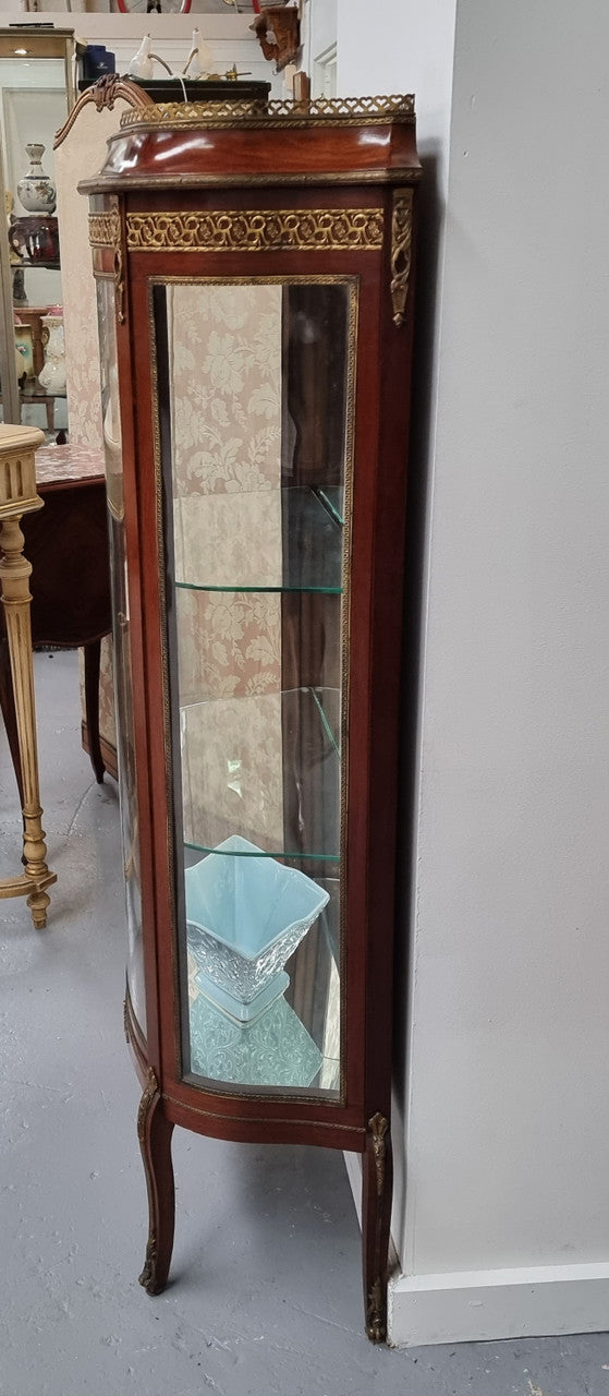 Beautiful French Louis XV style vitrine/ display cabinet with curved glass, gilt mounts, mirrored back and two glass shelves for your displays . It is in good original detailed condition.