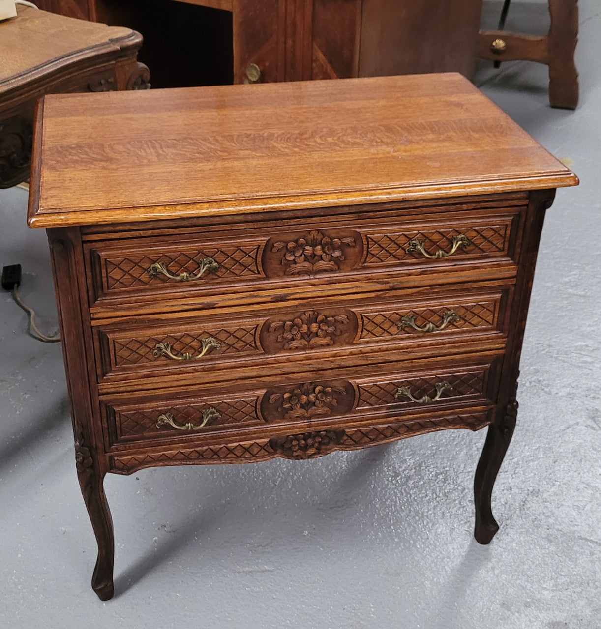 Rustic Louis XV style Oak petite three drawer chest featuring attractive carvings. It has been sourced locally and it is in good original detailed condition.