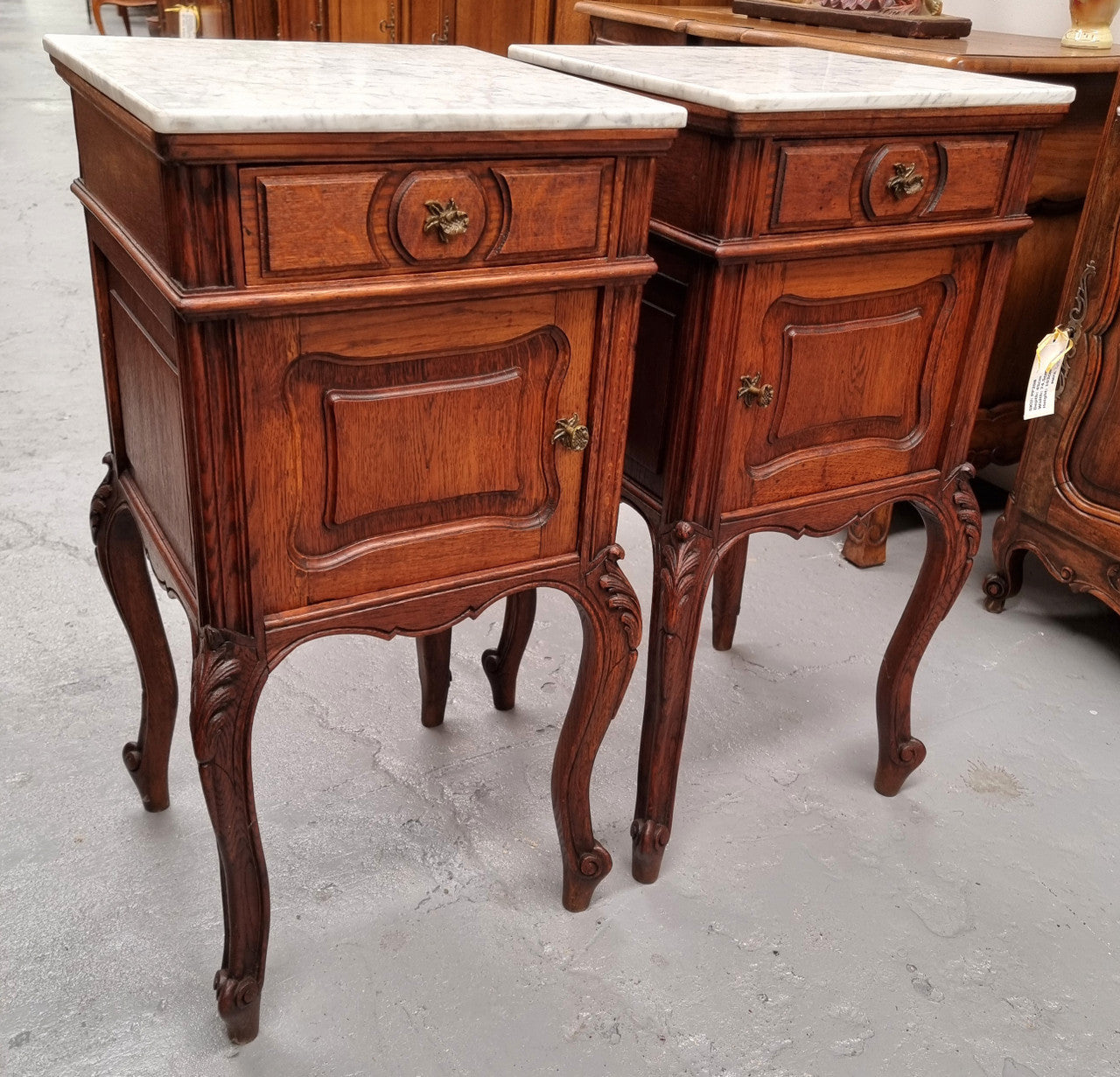Elegant French Louis XV style pair of carved Oak white marble top bedsides. They are in good original condition and they have been detailed to a high standard. They have been sourced from France.