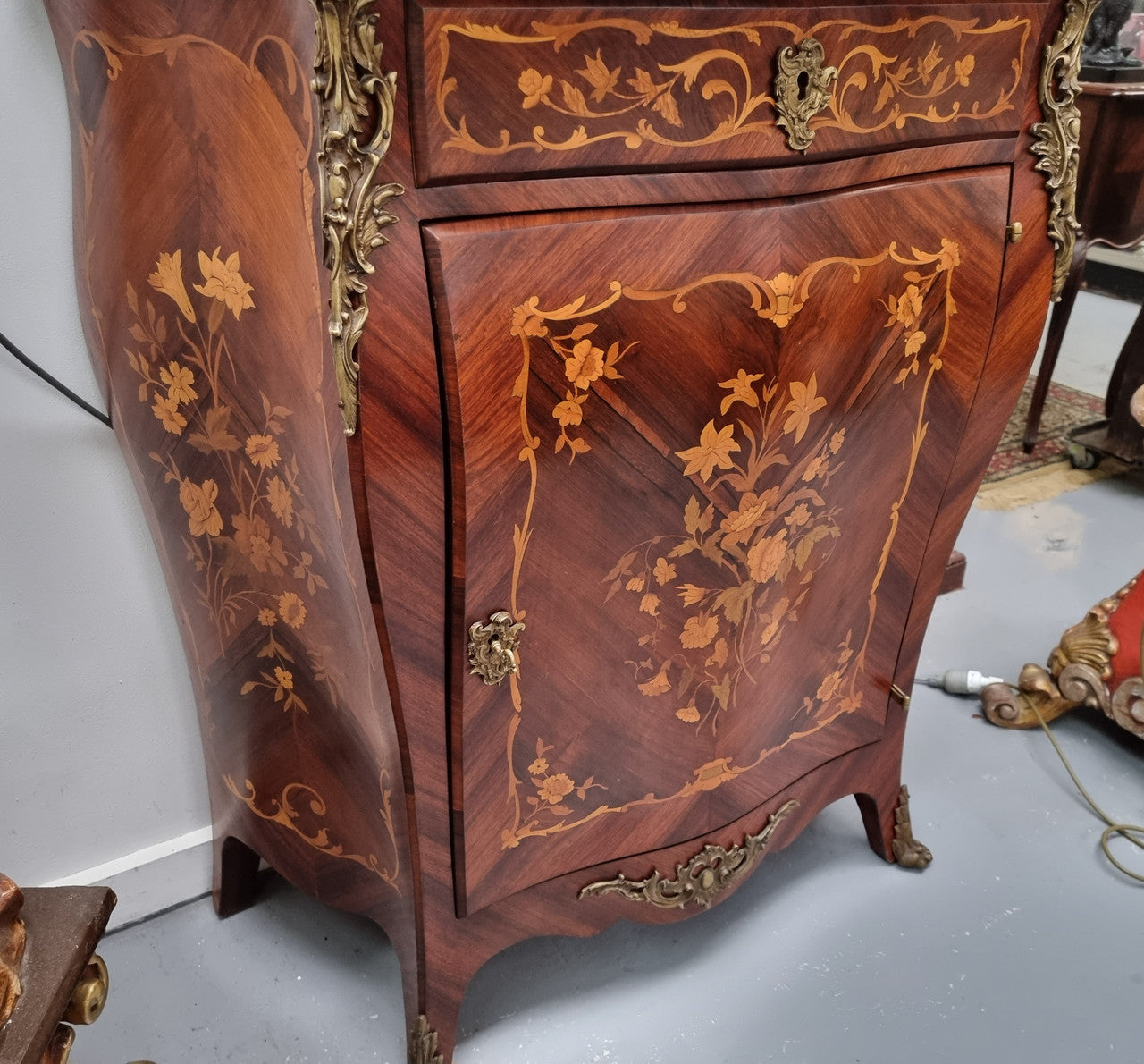 Stunning French Transitional style Mahogany marquetry inlay salon cabinet in the bombe shape. It has one draw, one shelf, marble top & ormolu decoration. Sourced from France and in good original detailed condition.