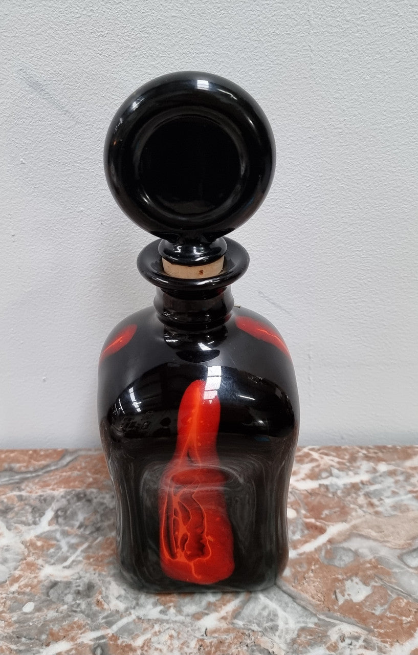 Vintage Designer glass carafe by “Stromit Handarbeit”. Dark background with flashes of orange/red.