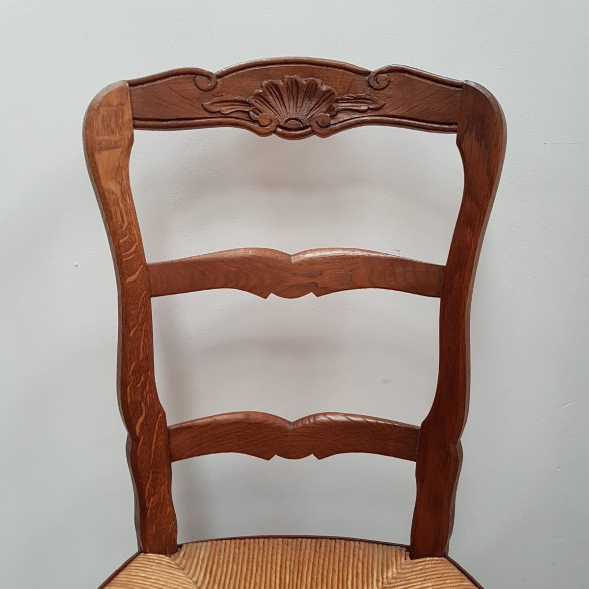 A set of six French Louis XV style, ladder back oak chairs. With finely carved detail and rush seat. In great original condition. Chairs are comfortable and sturdy for everyday use.