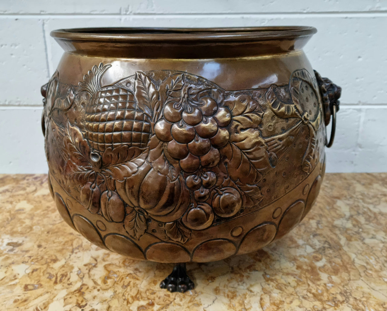 Antique large brass bronze coloured embossed Jardinière/planter with lovely details and lion heads for handles. It is in good original condition.