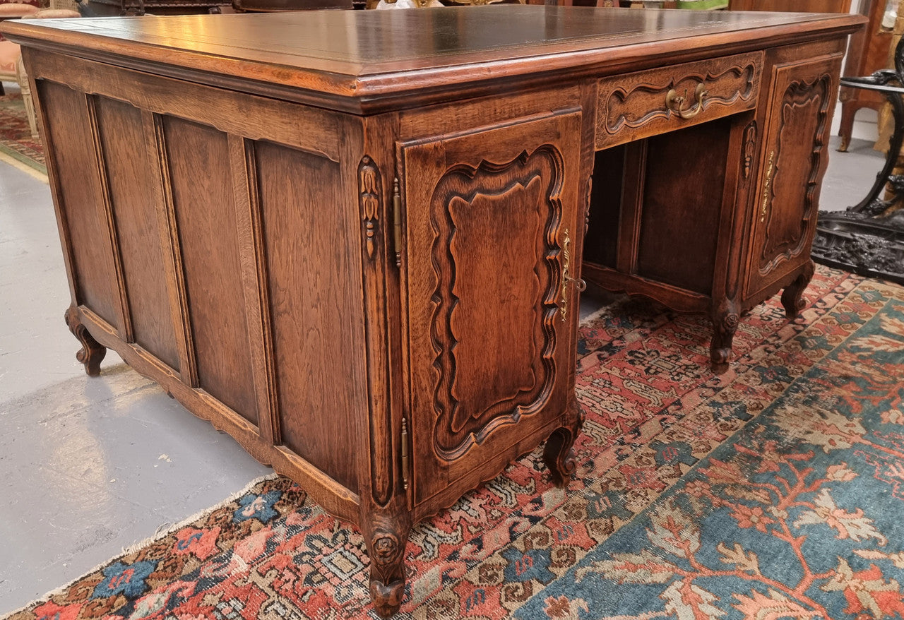 Fabulous Louis XV style French Oak beautifully carved full partners desk with an amazing tooled leather top. Both sides have a functioning drawer in the middle and two cupboards either side. On both sides one cupboard door opens up to four smaller internal drawers. Plenty of storage space and a large top surface to work on. It is in good original detailed condition.