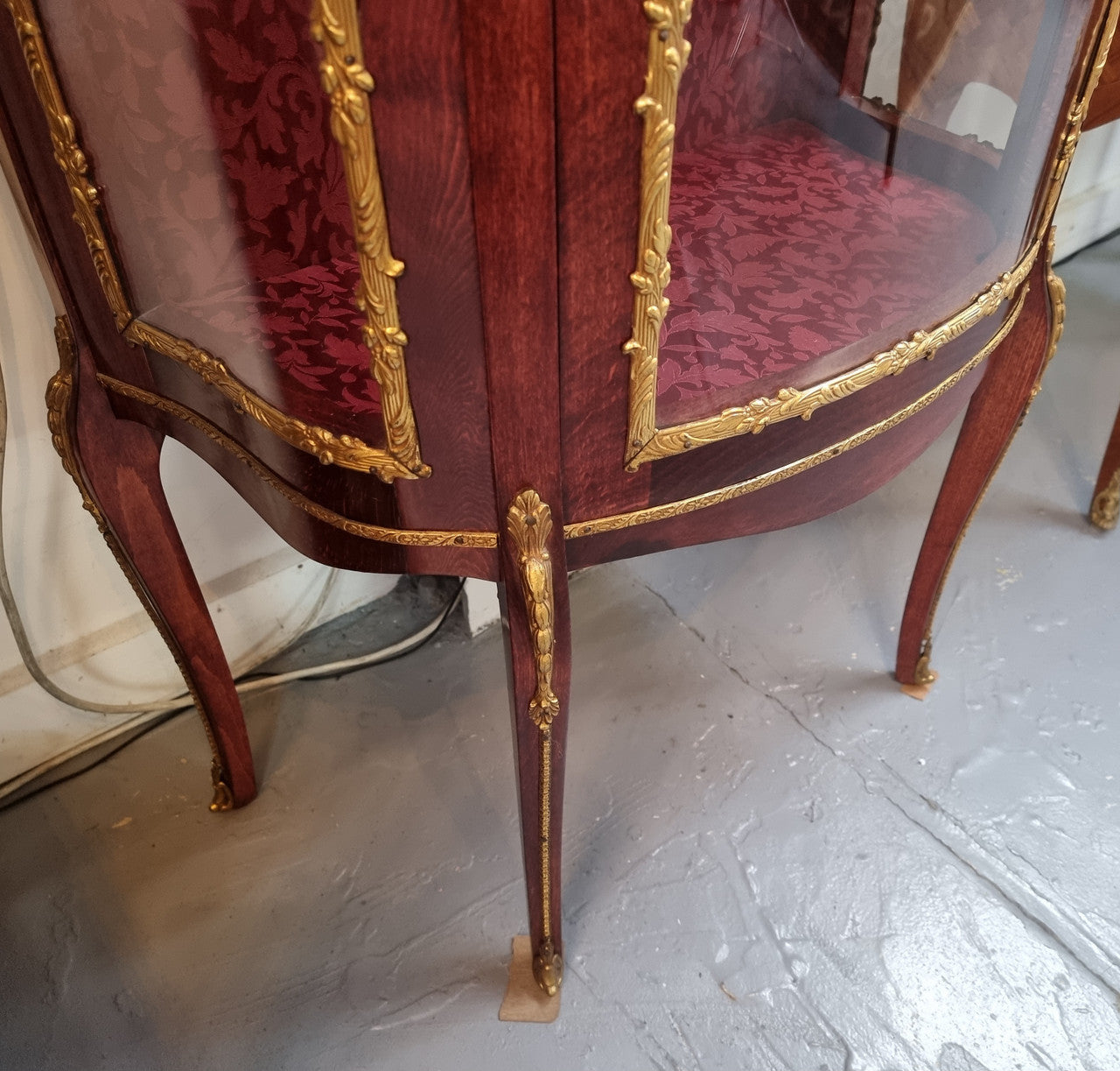 French Mahogany two shelf vitrine with curved glass and brass mounts. It has a lovely frabic interior and two glass shelves. In good original detailed condition.