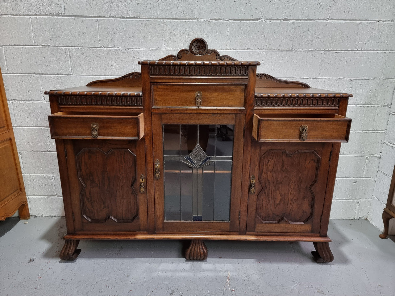 Lovely Oak Tudor style rope edge sideboard with leadlight center door, three drawers and two solid cupboards. In good original condition.