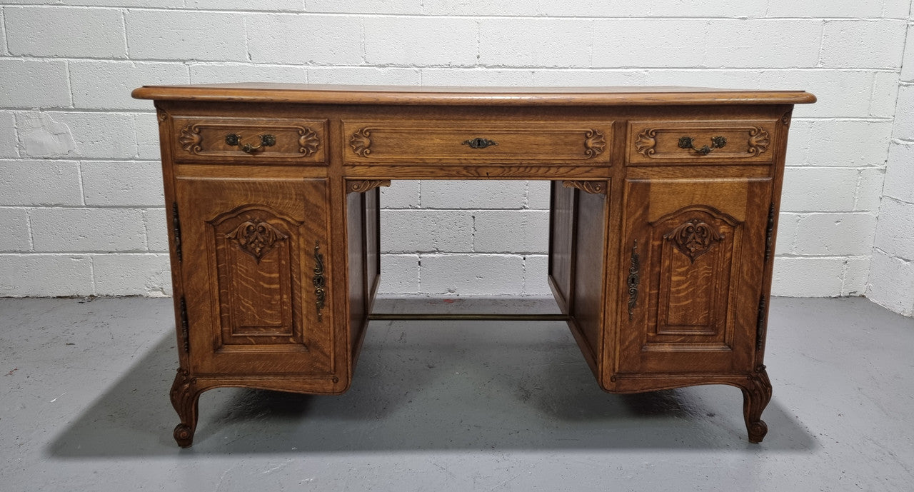 Fabulous French oak carved partners desk with a lovely parquetry top. It has three drawers and two cupboards on one side and two cupboards on the other side with no functioning drawers. It is in good original detailed condition.