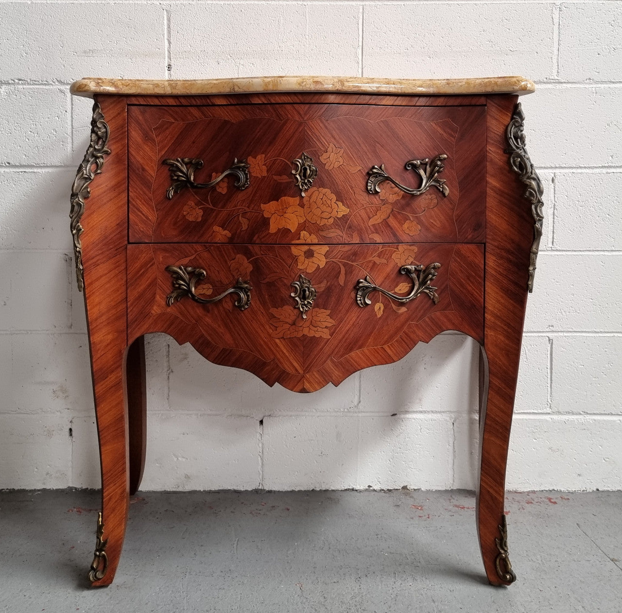 A timeless and compact French Louis XV style two drawer Kingwood marquetry inlaid commode. It features a stunning marble marble top and decorative mounts. The compact design of this commode ensures versatility, making it a perfect addition to any living space, bedroom or hallway. It has been sourced directly from France and is in good original detailed condition.