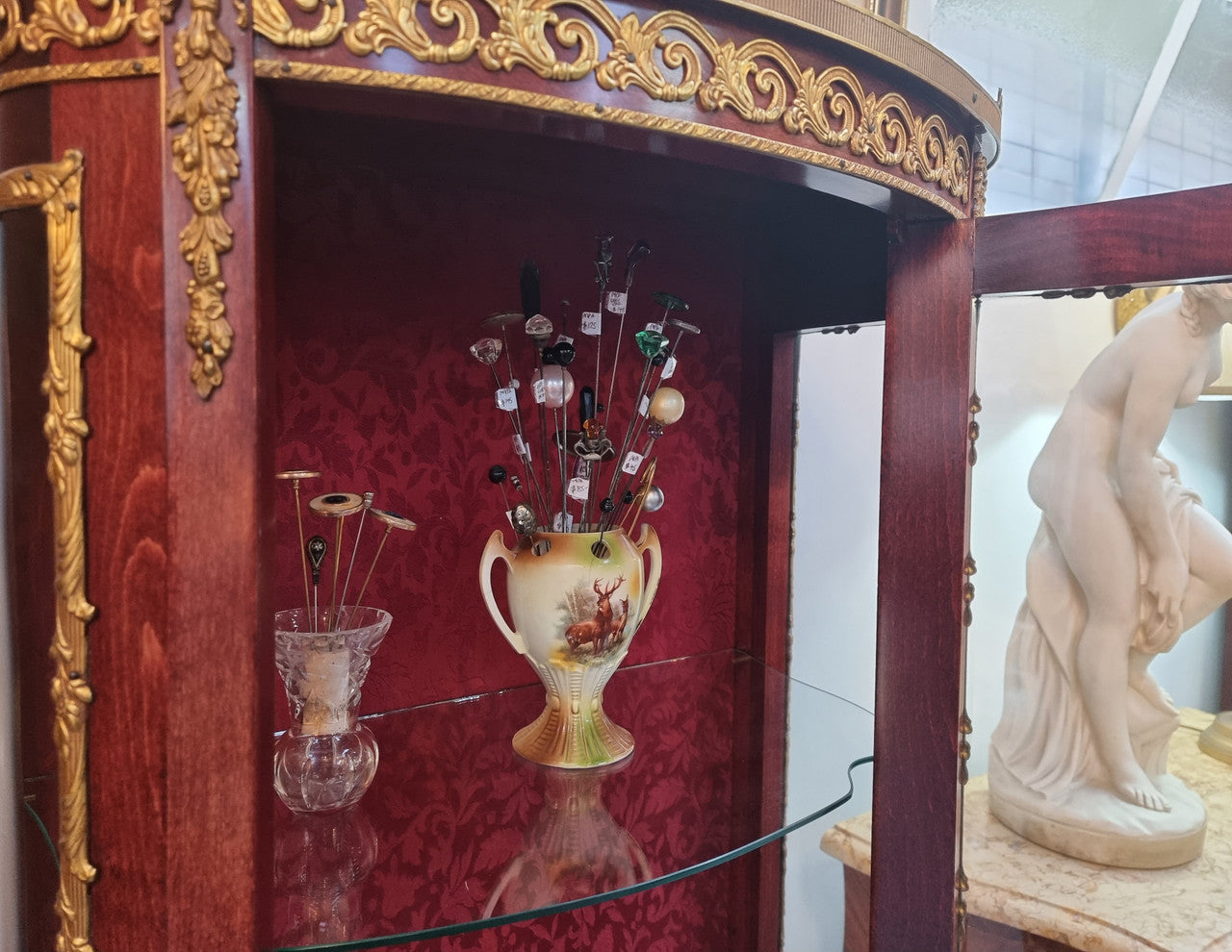 French Mahogany two shelf vitrine with curved glass and brass mounts. It has a lovely frabic interior and two glass shelves. In good original detailed condition.