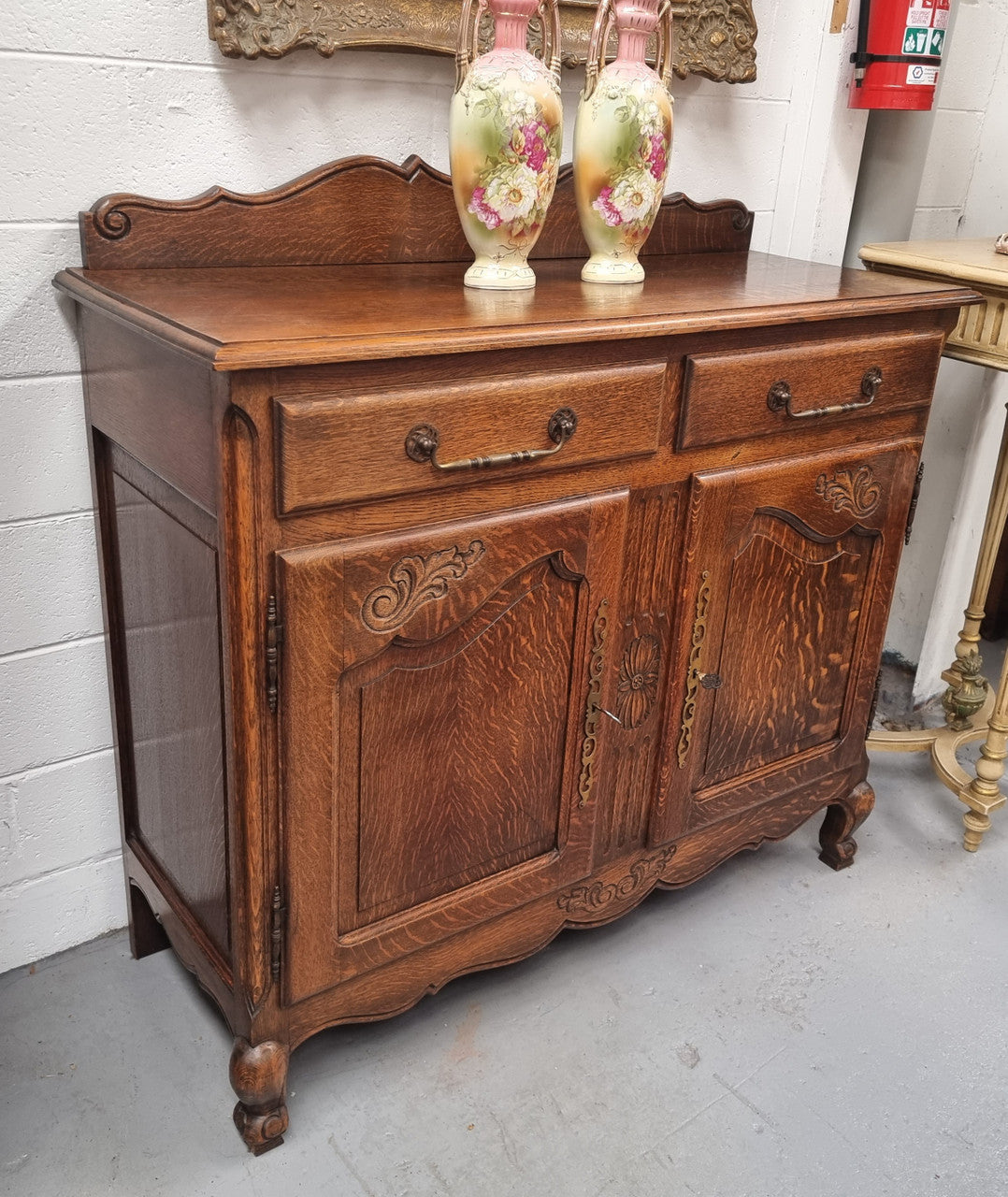 French Louis XV style Oak two door, two drawer sideboard. It is of pleasing narrow proportions and has one interior shelf. It has been sourced from France and it is in good original detailed condition.