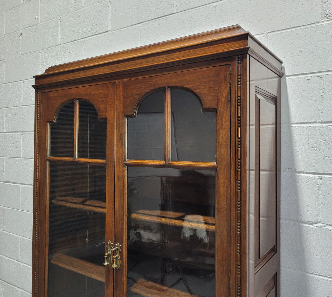 English Walnut two door bookcase with original glass. It has three adjustable shelves and hidden storage below behind two smaller doors. It is in food original condition.