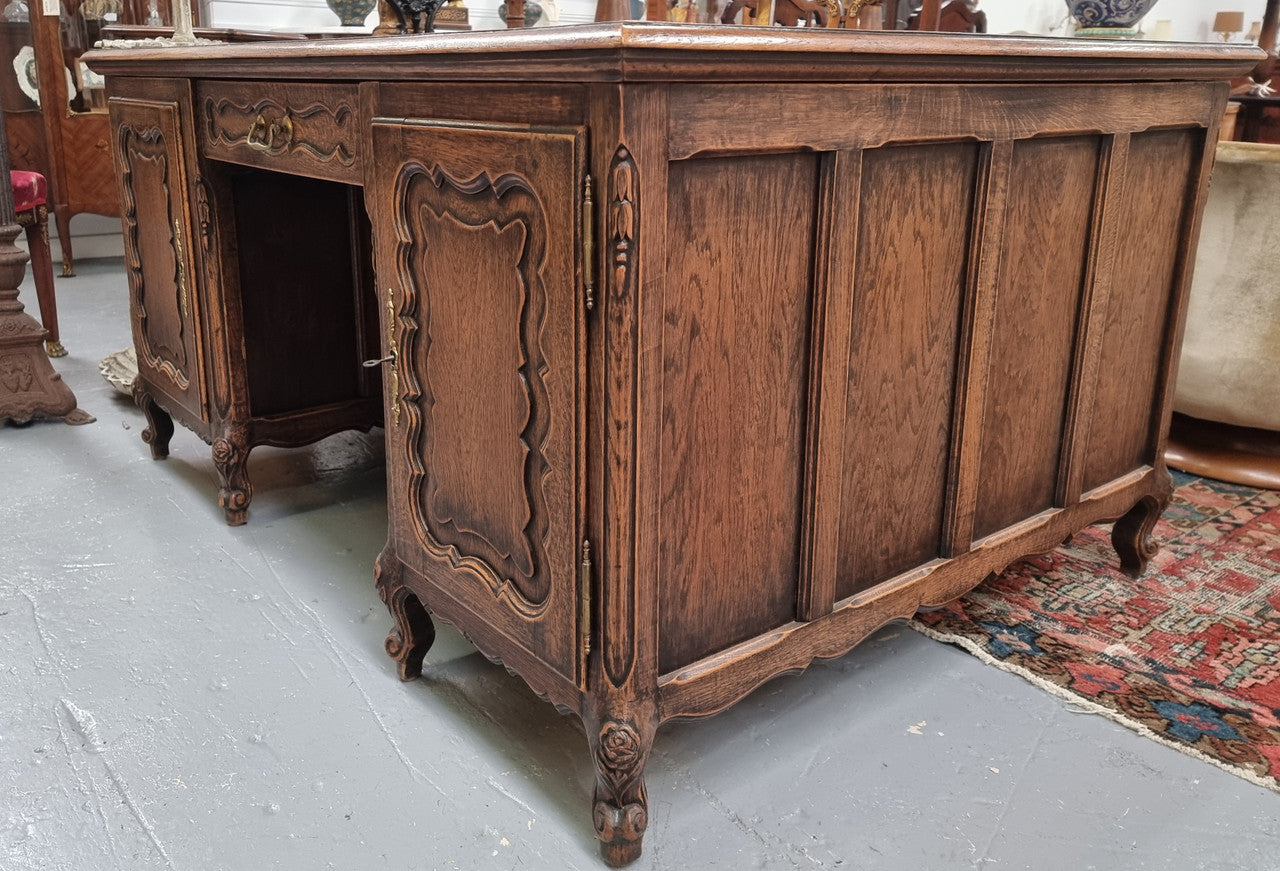 Fabulous Louis XV style French Oak beautifully carved full partners desk with an amazing tooled leather top. Both sides have a functioning drawer in the middle and two cupboards either side. On both sides one cupboard door opens up to four smaller internal drawers. Plenty of storage space and a large top surface to work on. It is in good original detailed condition.