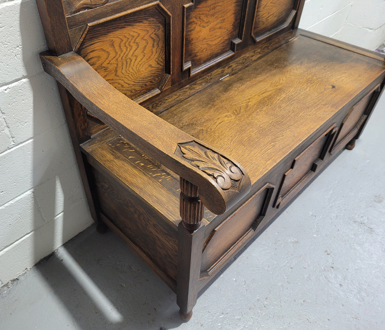 English Oak Tudor style hall seat with lift up top and a storage compartment underneath. It is in good original detailed condition with its original finish.