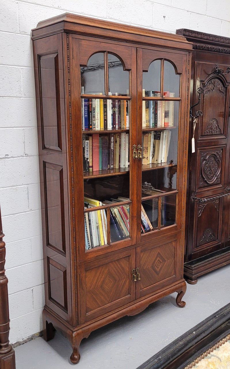 Beautiful four door Walnut bookcase with glass doors. The top section has two fully adjustable shelves and it is of pleasing narrow proportions. It is in good original detailed condition.