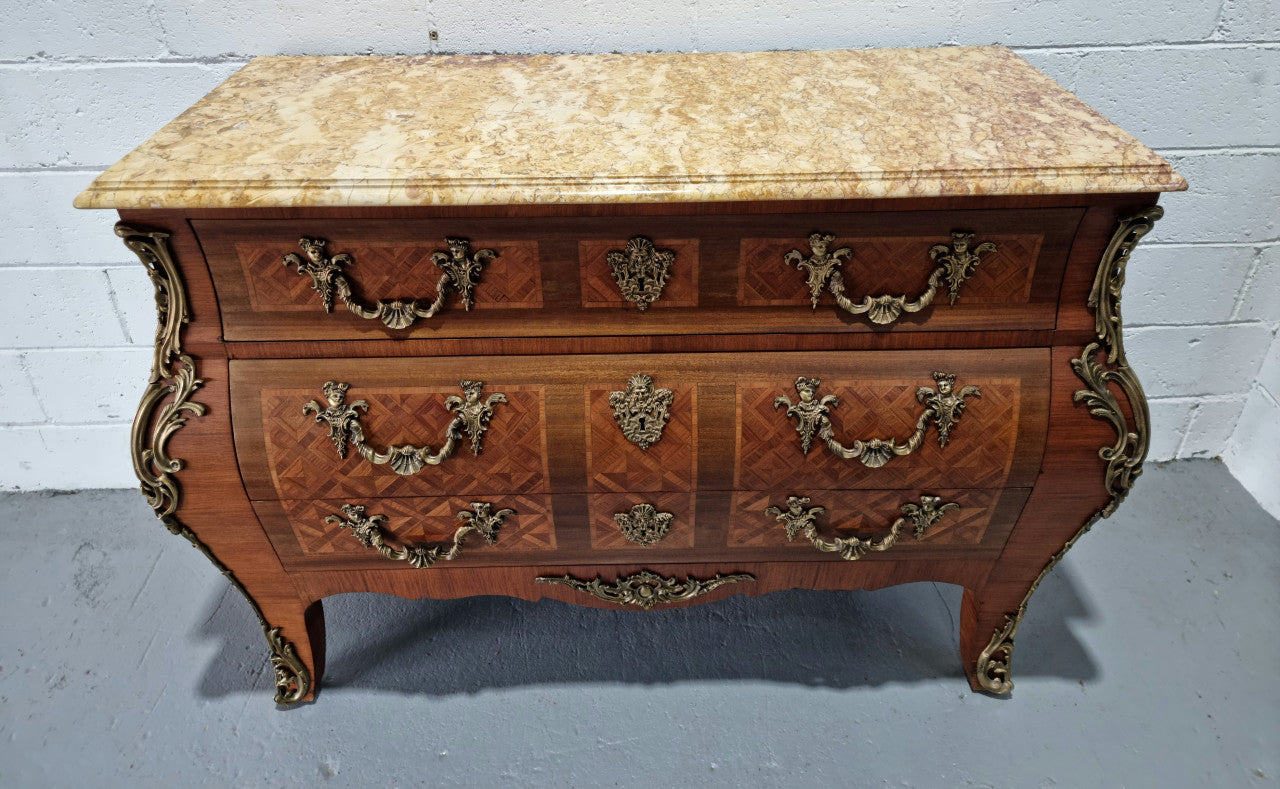 A beautifully inlaid parquetry three drawer commode with a lovely marble top, and decorative ormolu mounts. In good original detailed condition. Circa 1930