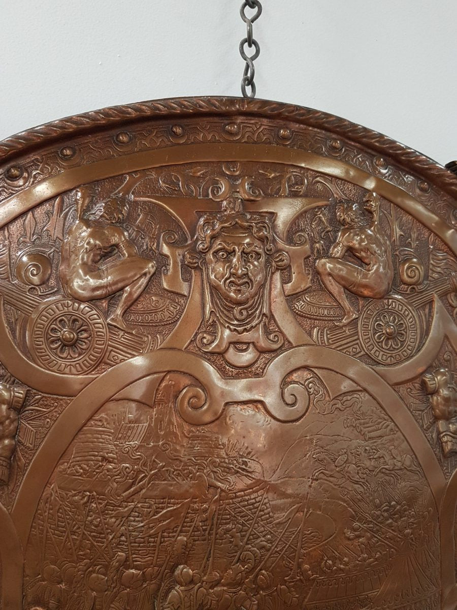A beautiful European antique repousse copper shield, depicting a battle scene and with metal swords. It has been sourced from France and is in good original condition.