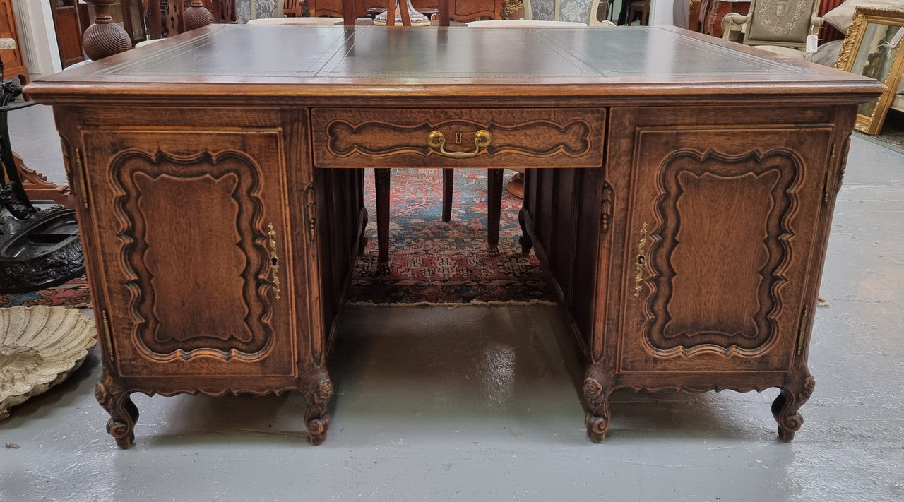 Fabulous Louis XV style French Oak beautifully carved full partners desk with an amazing tooled leather top. Both sides have a functioning drawer in the middle and two cupboards either side. On both sides one cupboard door opens up to four smaller internal drawers. Plenty of storage space and a large top surface to work on. It is in good original detailed condition.