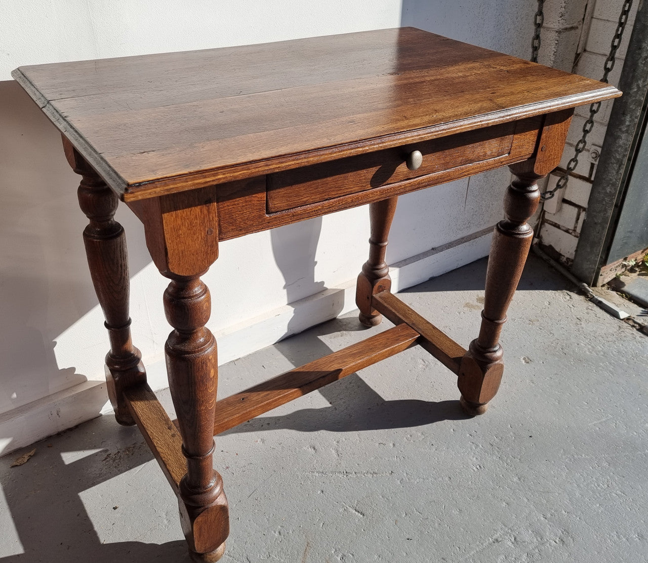 Rustic French Oak side table or desk with single drawer and turned legs. In good original detailed condition.
