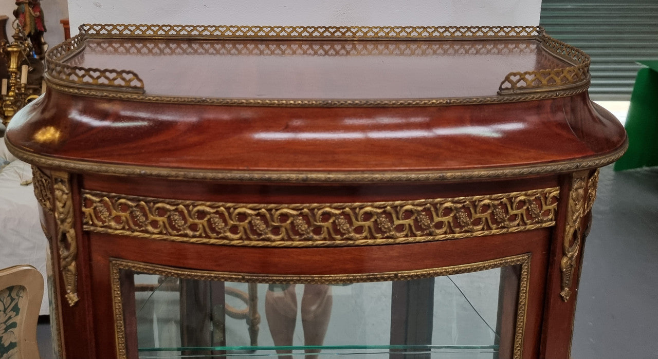 Beautiful French Louis XV style vitrine/ display cabinet with curved glass, gilt mounts, mirrored back and two glass shelves for your displays . It is in good original detailed condition.