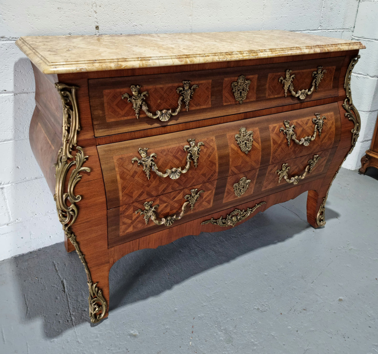 A beautifully inlaid parquetry three drawer commode with a lovely marble top, and decorative ormolu mounts. In good original detailed condition. Circa 1930