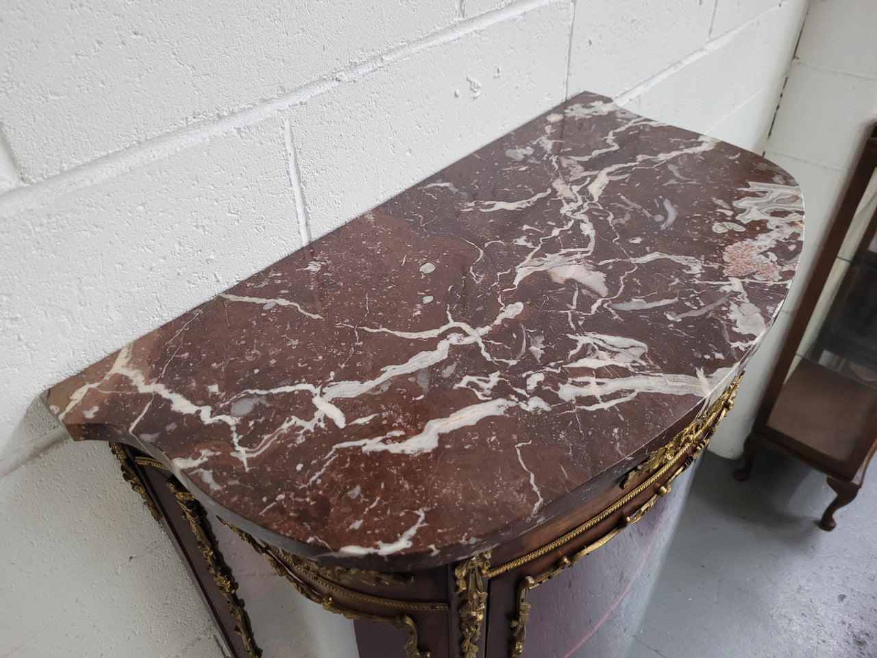 Louis XV style Vitrine with curved glass and red velvet lining. It has two fixed shelves with a marble top and ormolu decoration. In good original detailed condition.