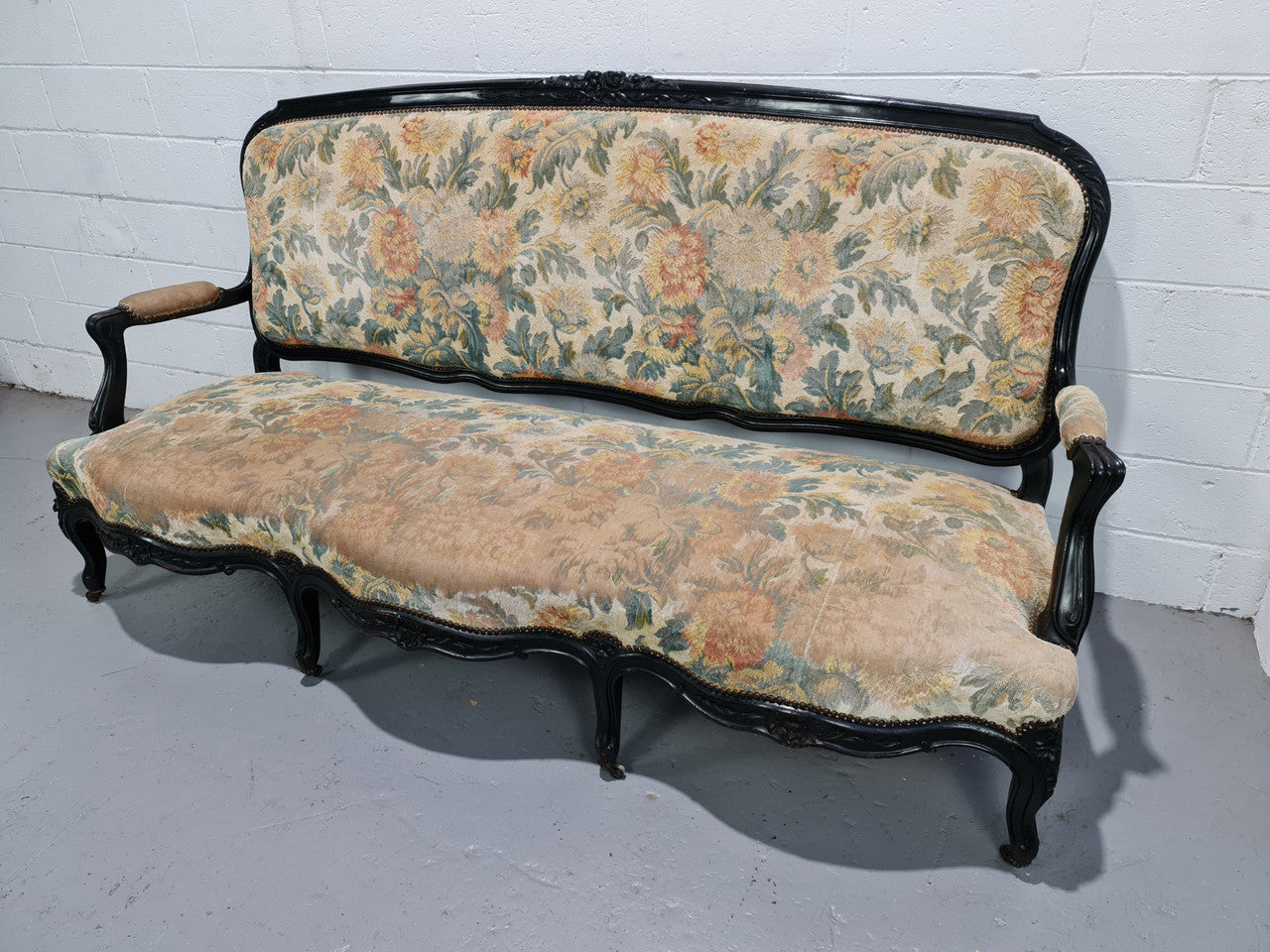 A Substantial Antique 19th Century Louis XV style ebonized serpentine front settee. The fabric is in used condition showing use and could be used as is or reupholster.