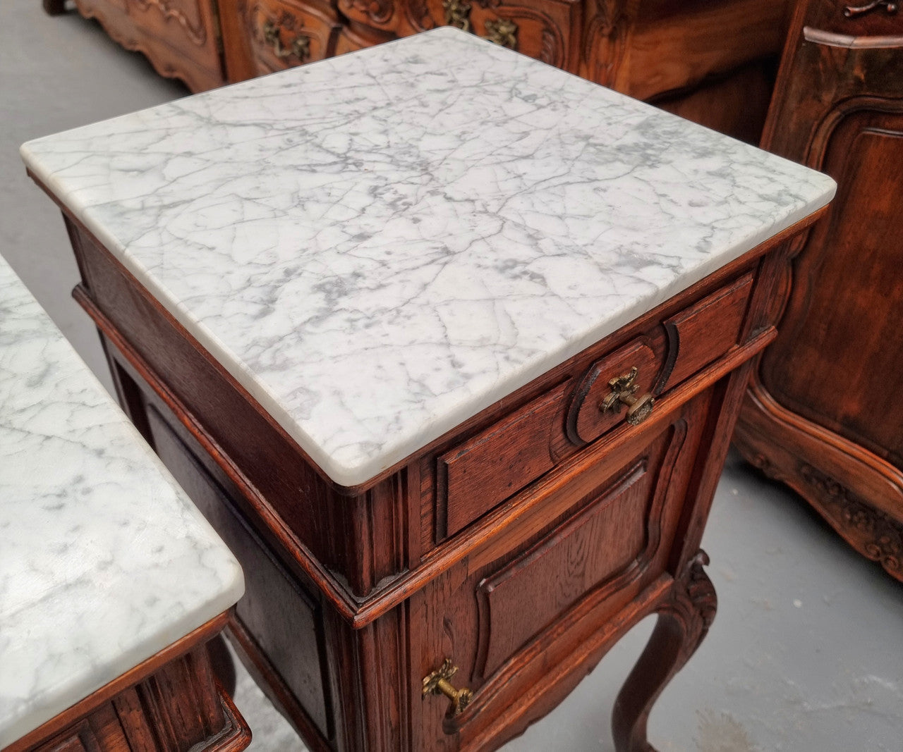 Elegant French Louis XV style pair of carved Oak white marble top bedsides. They are in good original condition and they have been detailed to a high standard. They have been sourced from France.