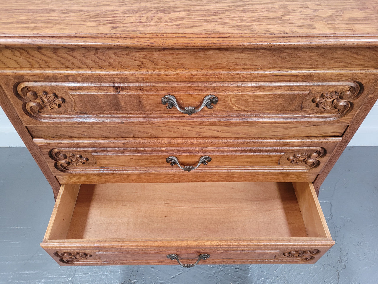 Vintage French light Oak Louis XV style chest of three drawers. It has beautiful cabriole legs, elegant brass handles and carvings. It is in good original detailed condition and has been sourced from France.