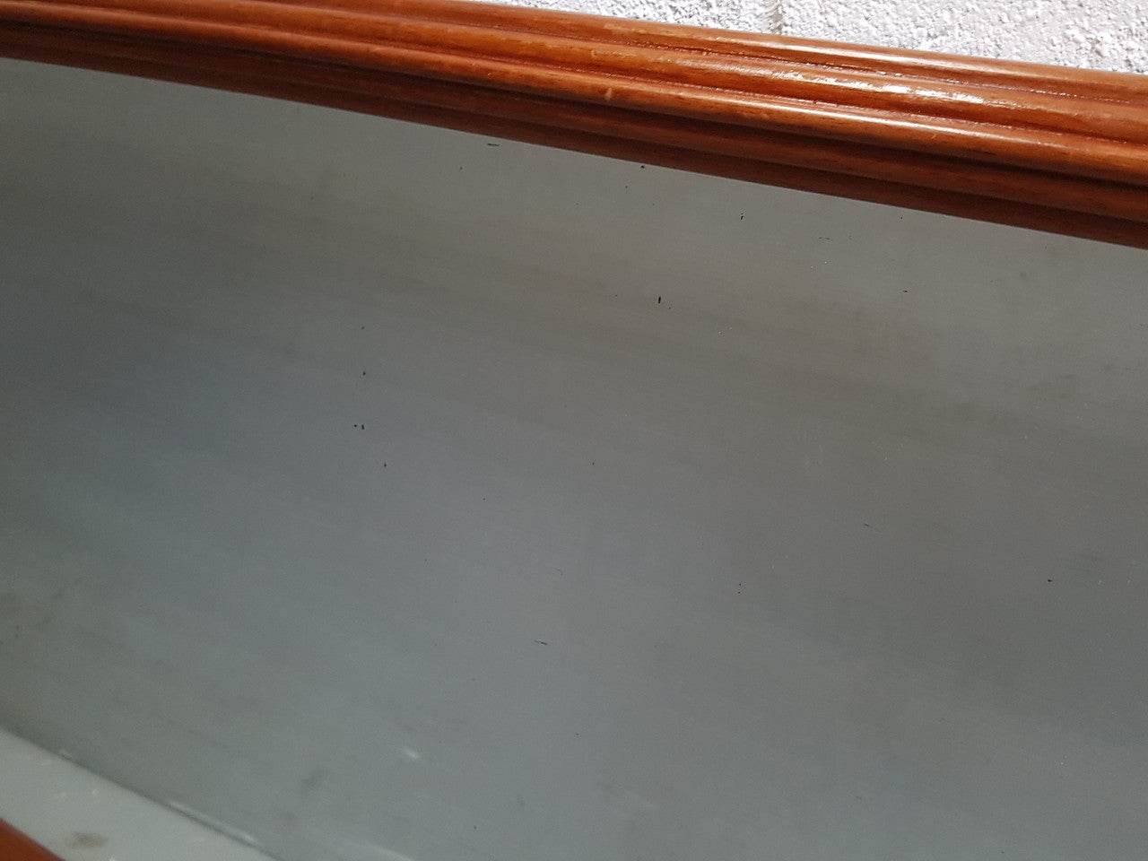Art Deco mahogany mirror of long and narrow portions. In good original condition and retaining it's original mirror.
