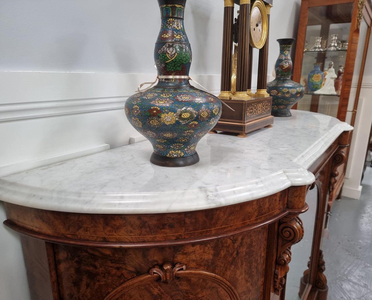 An elegant Antique Victorian Burr wood Walnut marble-top sideboard credenza with a mirrored center door. It has a white shaped marble top, mirror front, nicely carved details and three swing doors along with two keys. It is in good original detailed condition.