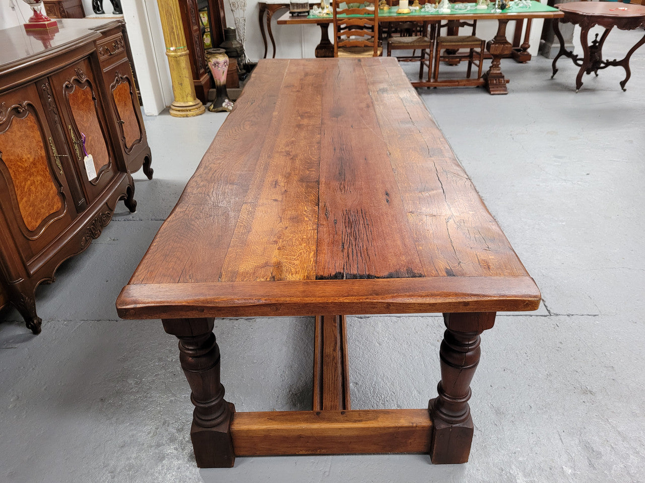 Charming solid rustic Oak stretcher base Farmhouse table. The table is circa 1950's and was custom made using reclaimed oak. It comfortable sits eight and could seat 10. It is in good original detailed condition.