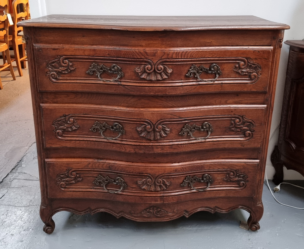 Antique French beautifully carved dark Oak commode with three drawers and ornate handles. It is in good original detailed condition.