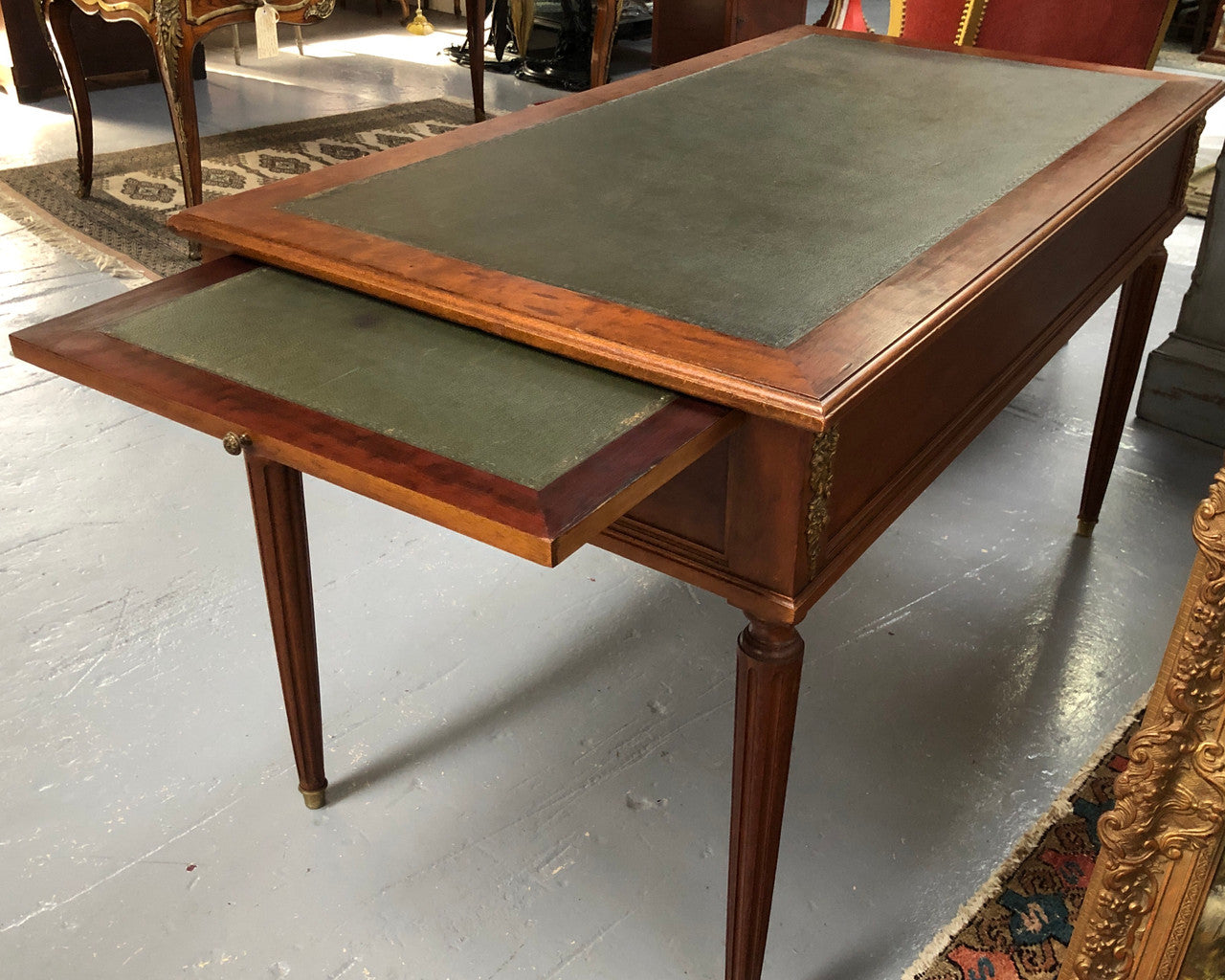 Lovely French Mahogany Louis XVI style leather top desk. With beautiful ormolu details and three drawers. There are also two slides on either side with tooled leather tops and in good original detailed condition.