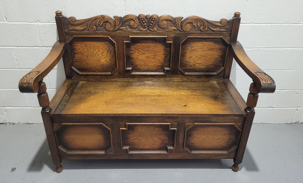 English Oak Tudor style hall seat with lift up top and a storage compartment underneath. It is in good original detailed condition with its original finish.
