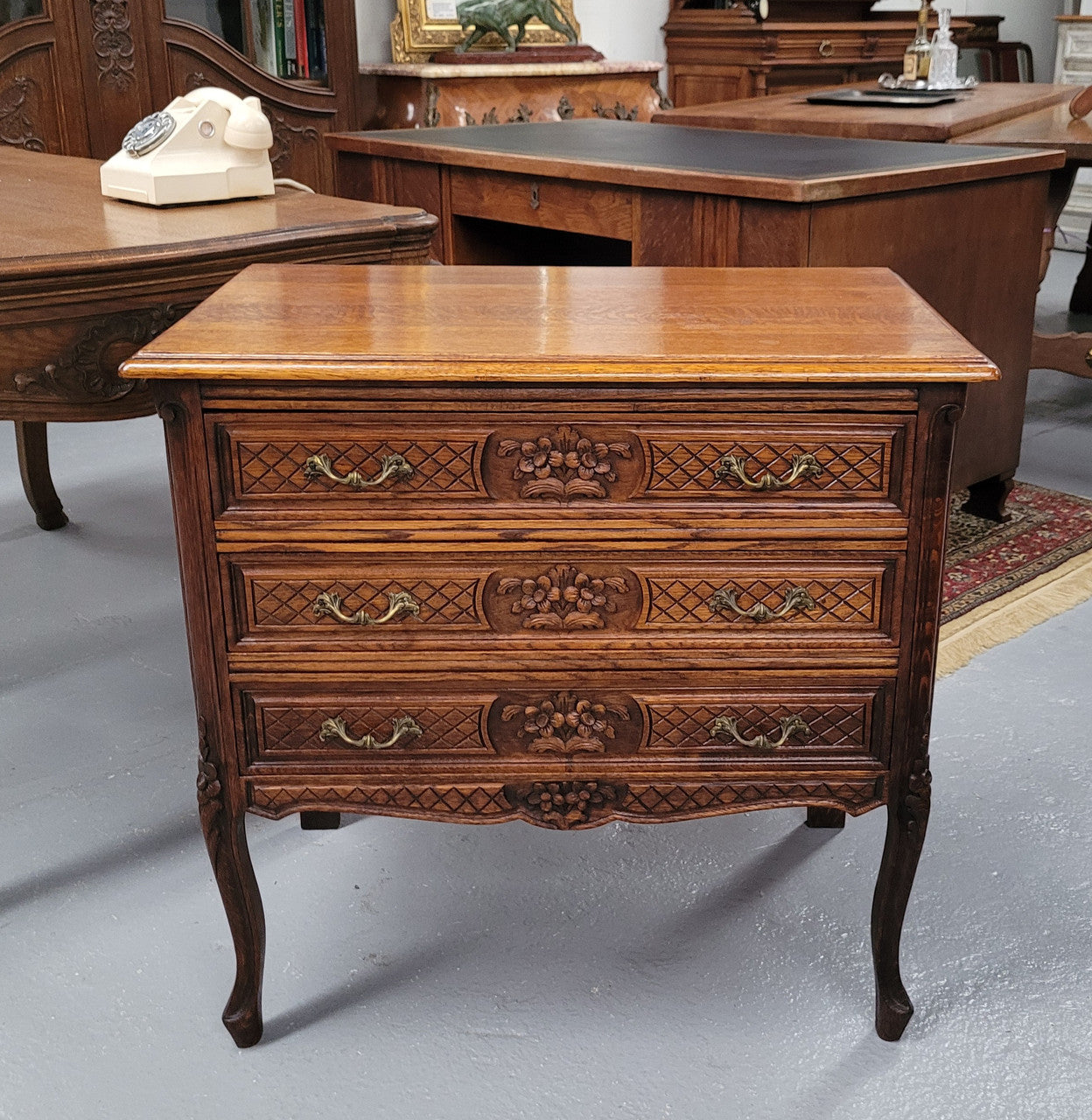 Rustic Louis XV style Oak petite three drawer chest featuring attractive carvings. It has been sourced locally and it is in good original detailed condition.