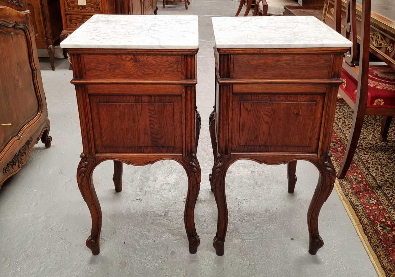 Elegant French Louis XV style pair of carved Oak white marble top bedsides. They are in good original condition and they have been detailed to a high standard. They have been sourced from France.