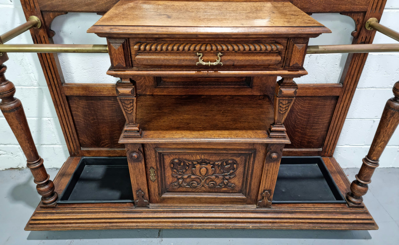 Grand Henry 2nd Style French Oak hall stand with 12 hanging hooks. Also has one cupboard and drawer for storage along with a mirror and two areas either side for umbrellas and walking sticks. In good original detailed condition.