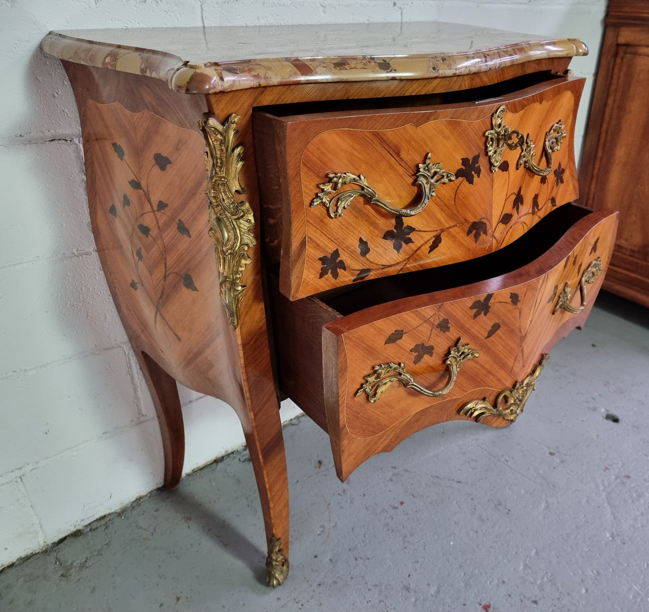 Charming petite French Louis XV style commode featuring two drawers, marquetry inlay, ormolu trim and marble Top. In good original detailed condition. Circa: 1930’s.