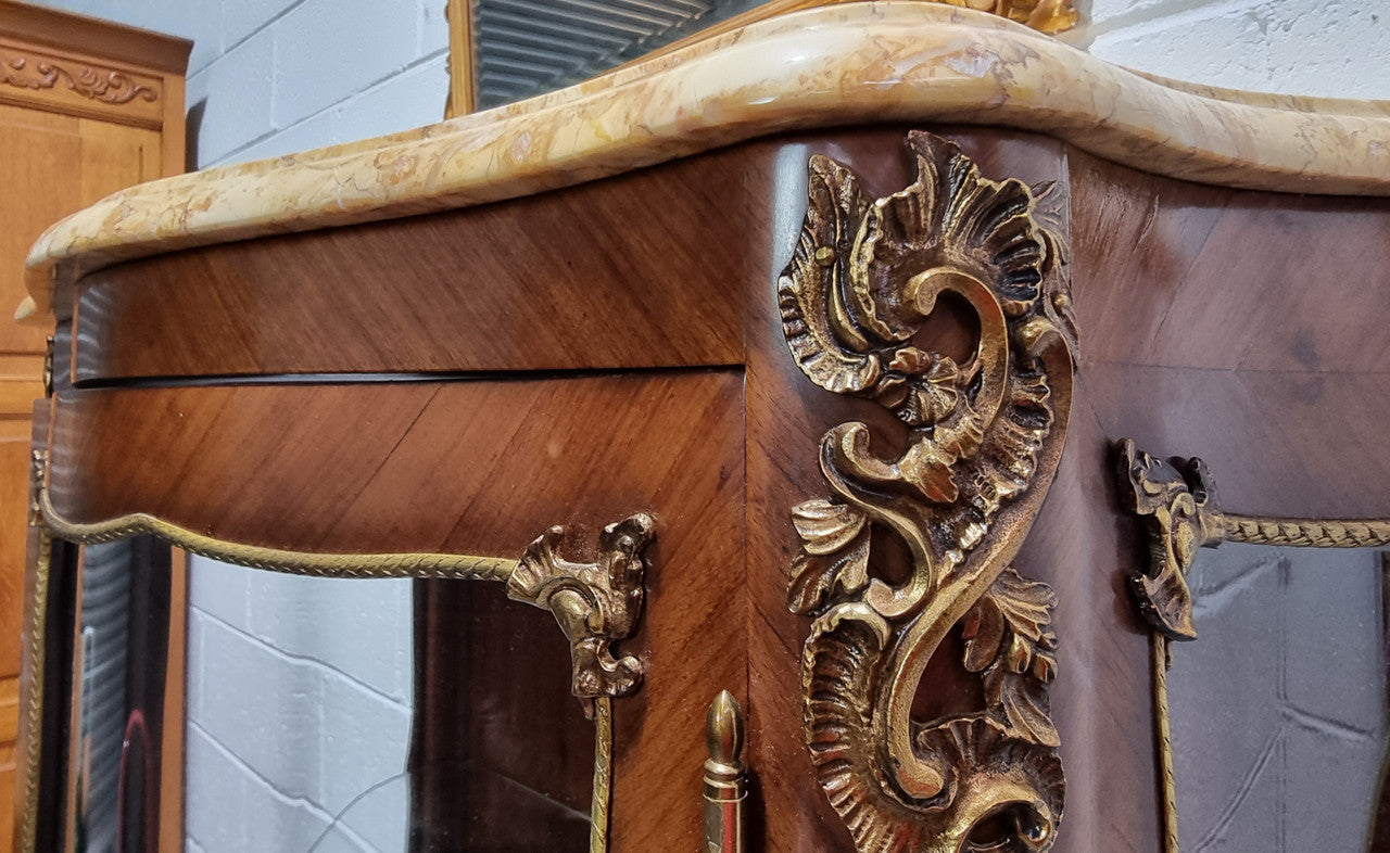 Grand French Walnut Louis XV style marble top vitrine. It has two glass shelfs and one mirrored shelf at the bottom and added storage at bottom. It is in good original detailed condition.