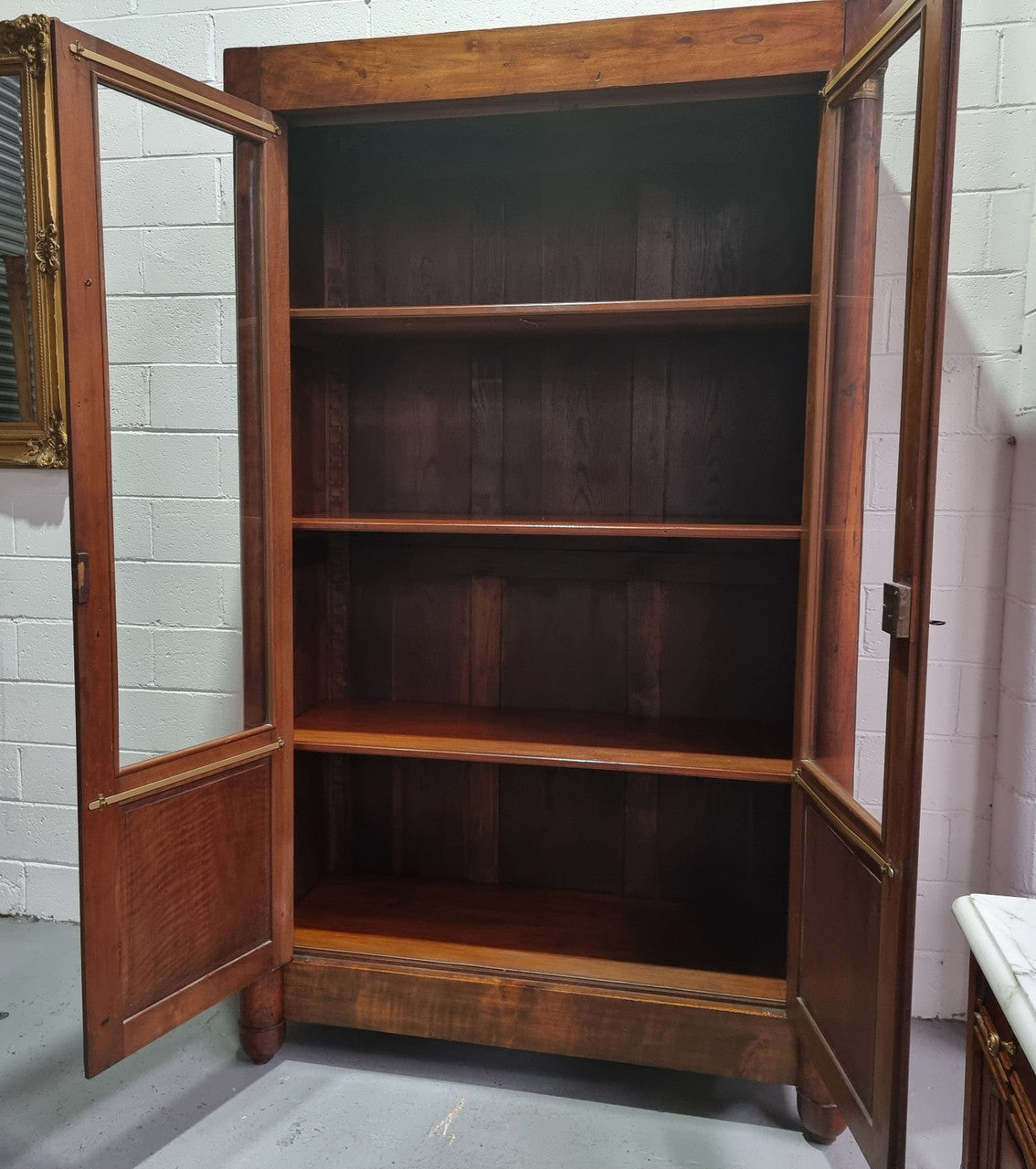 Grand French Mahogany Empire two door bookcase. It has beautiful glass doors and has three fully adjustable shelves. It has been sourced from France and is in good original detailed condition.