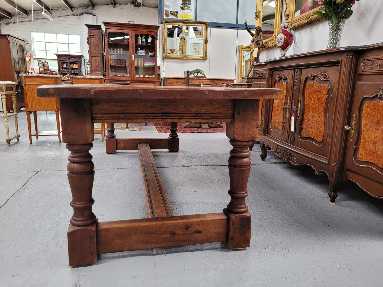 Charming solid rustic Oak stretcher base Farmhouse table. The table is circa 1950's and was custom made using reclaimed oak. It comfortable sits eight and could seat 10. It is in good original detailed condition.