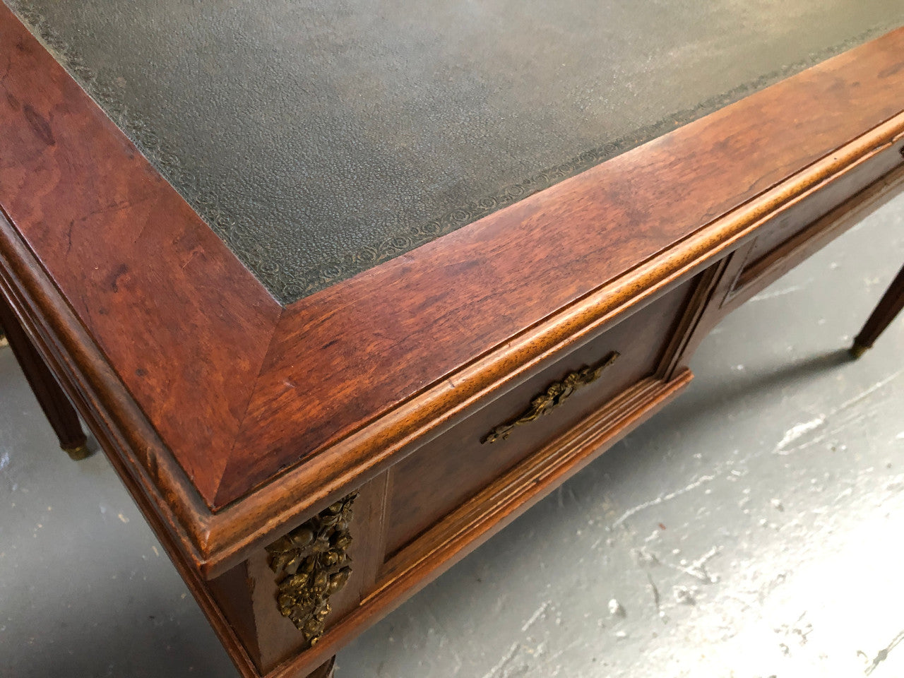 Lovely French Mahogany Louis XVI style leather top desk. With beautiful ormolu details and three drawers. There are also two slides on either side with tooled leather tops and in good original detailed condition.
