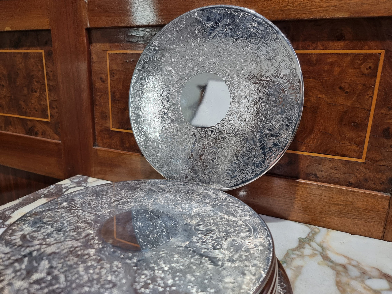 Five Strachan and two Rodd silver plate table coasters in a silver plate stand. In good original detailed condition.