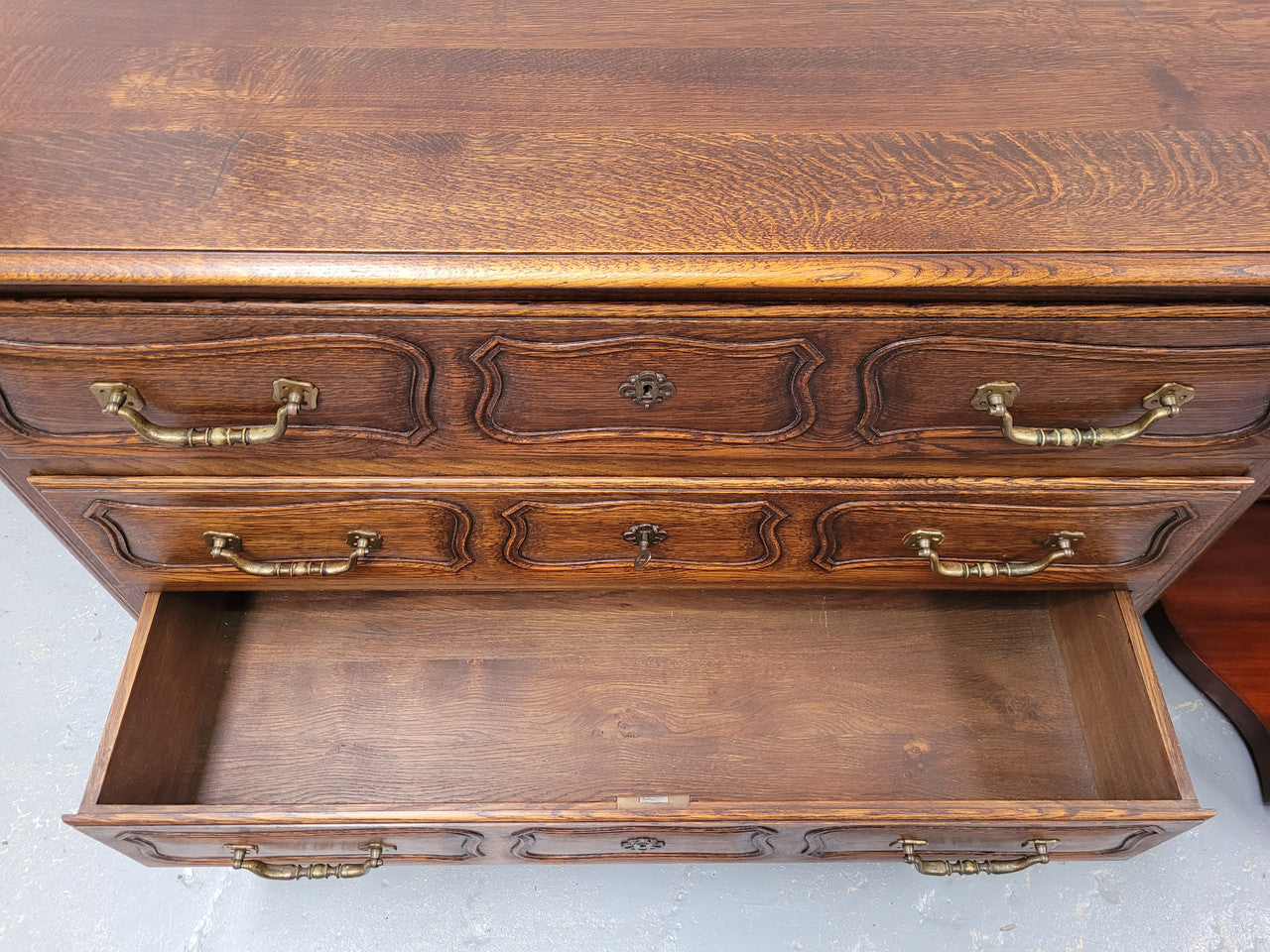 French Provincial Oak three drawer wooden top commode. It has elegant carvings and handles. It has been sourced from France and is in good original detailed condition.