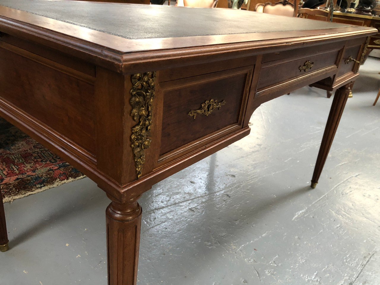 Lovely French Mahogany Louis XVI style leather top desk. With beautiful ormolu details and three drawers. There are also two slides on either side with tooled leather tops and in good original detailed condition.