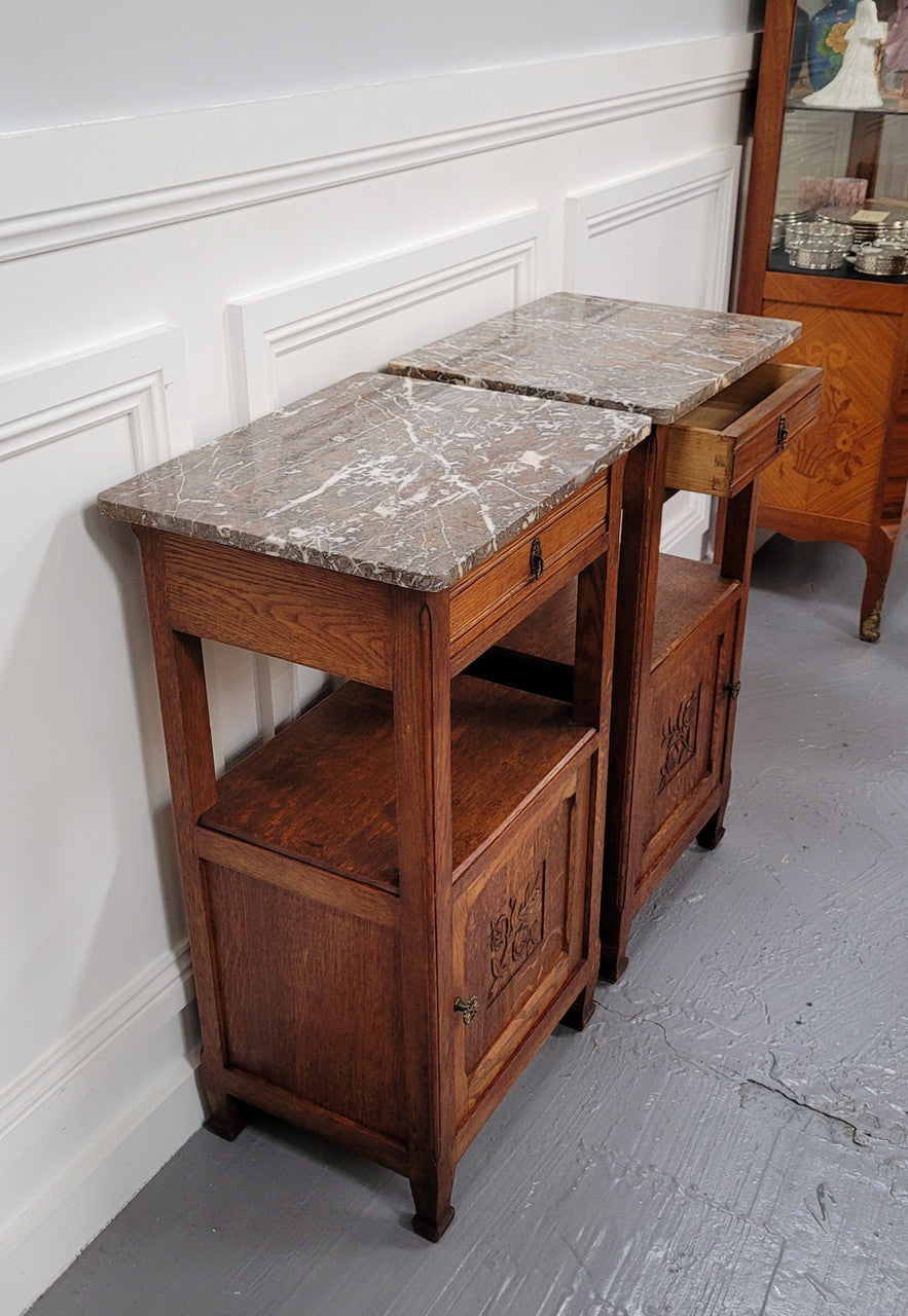 Pair of French Oak Arts & Crafts style marble top bedside cabinets. They have lovely carvings on the door, an open shelf in the middle and drawer at the top. They are in good original detailed condition.